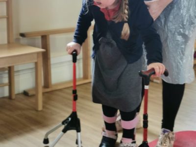 A little girl with walking sticks at Megan Baker House